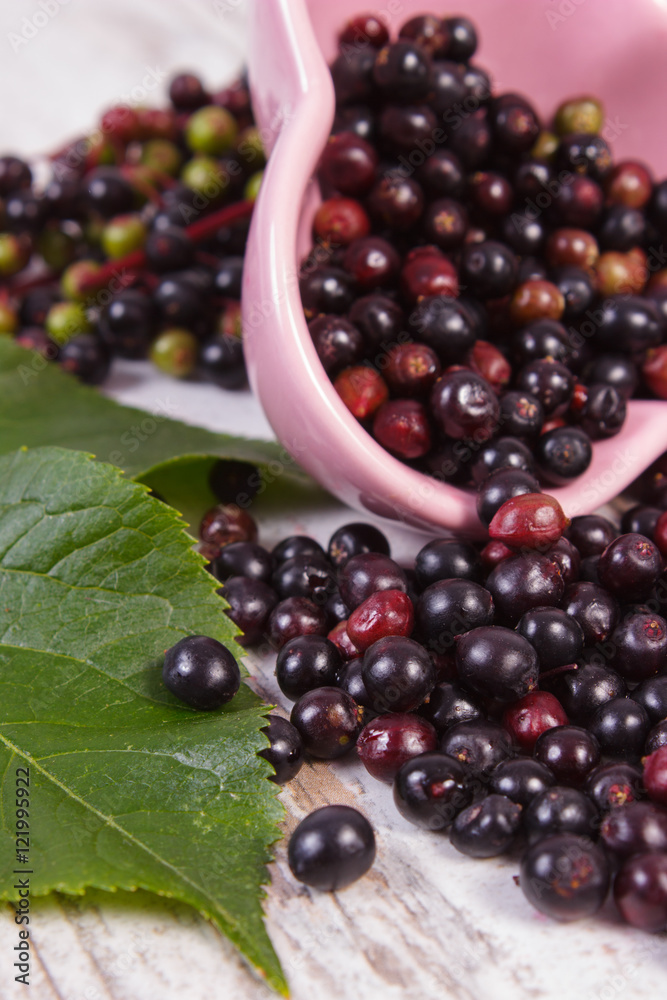 Fresh elderberry with leaf in glass dish on old wooden background Fresh elderberry with leaf in glass dish on old wooden background