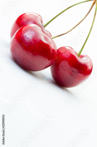 Three ripe cherries on a white background