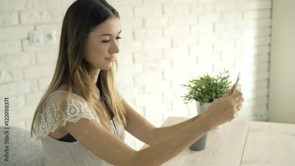 Young woman taking selfie photo with cellphone sitting by table at home
Young woman taking selfie photo with cellphone sitting by table at home