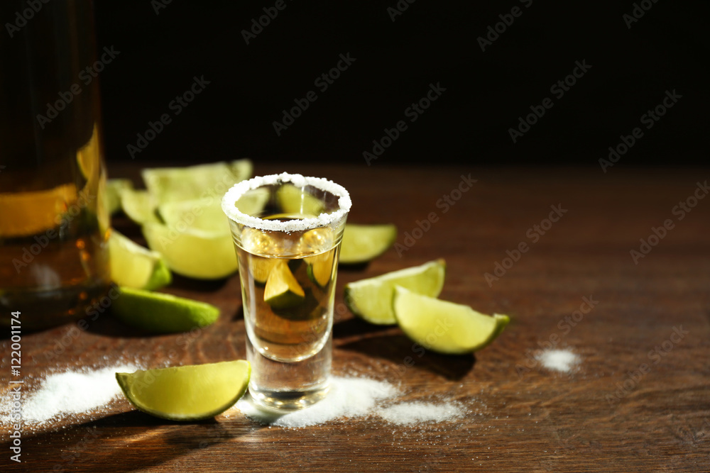Gold tequila shot with lime and salt on wooden table Gold tequila shot with lime and salt on wooden table
