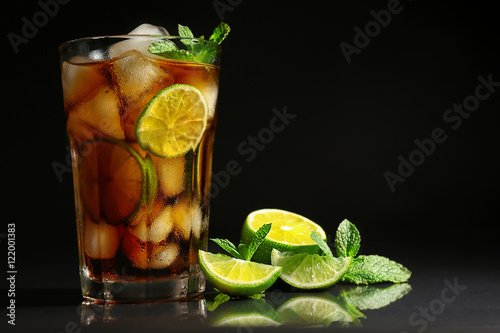 Cuba libre cocktail with lime and mint on dark background