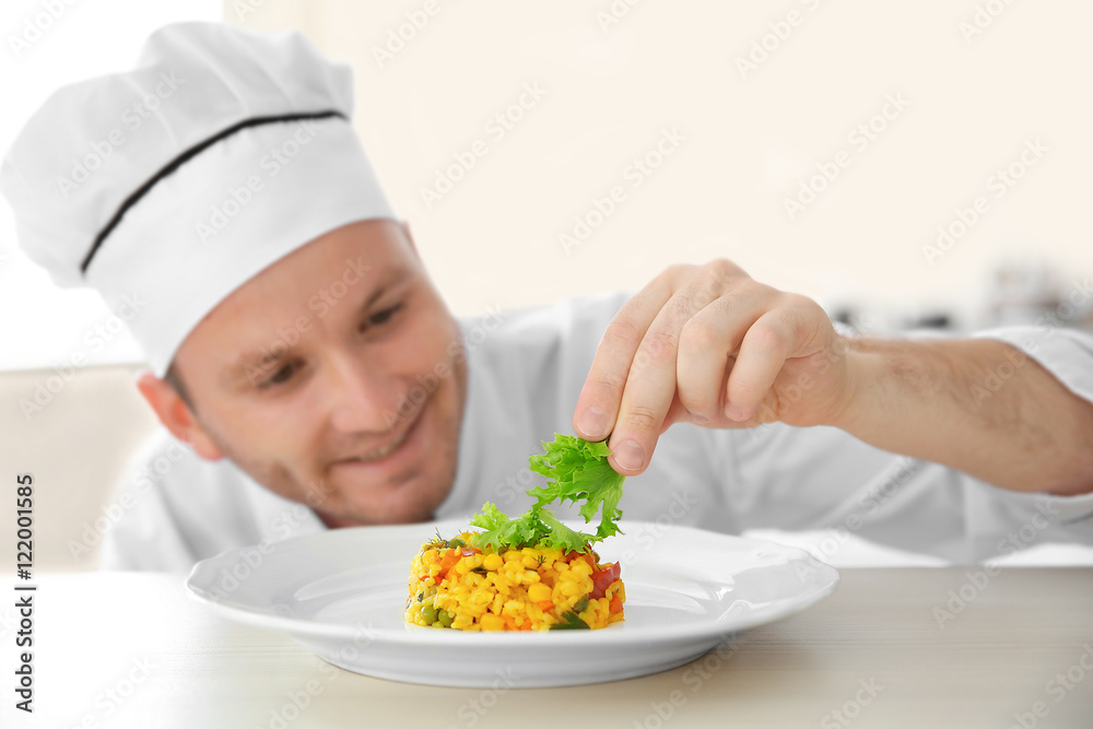Young chef cook decorating dish in kitchen Young chef cook decorating dish in kitchen