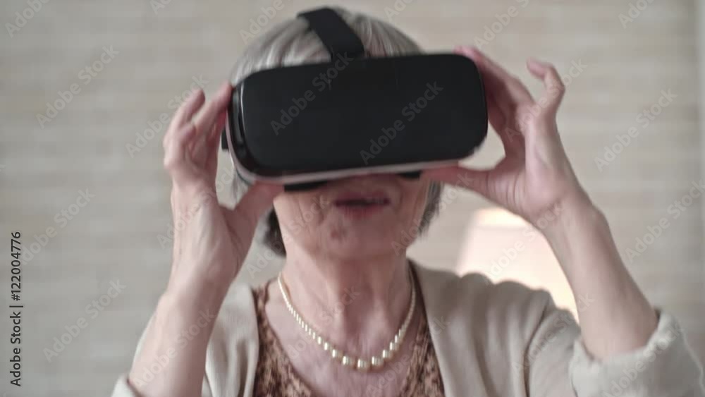 Slow motion of elderly woman in virtual reality headset widely smiling and jumping up and down Slow motion of elderly woman in virtual reality headset widely smiling and jumping up and down