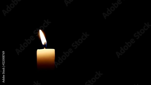 Burning candle on dark background.