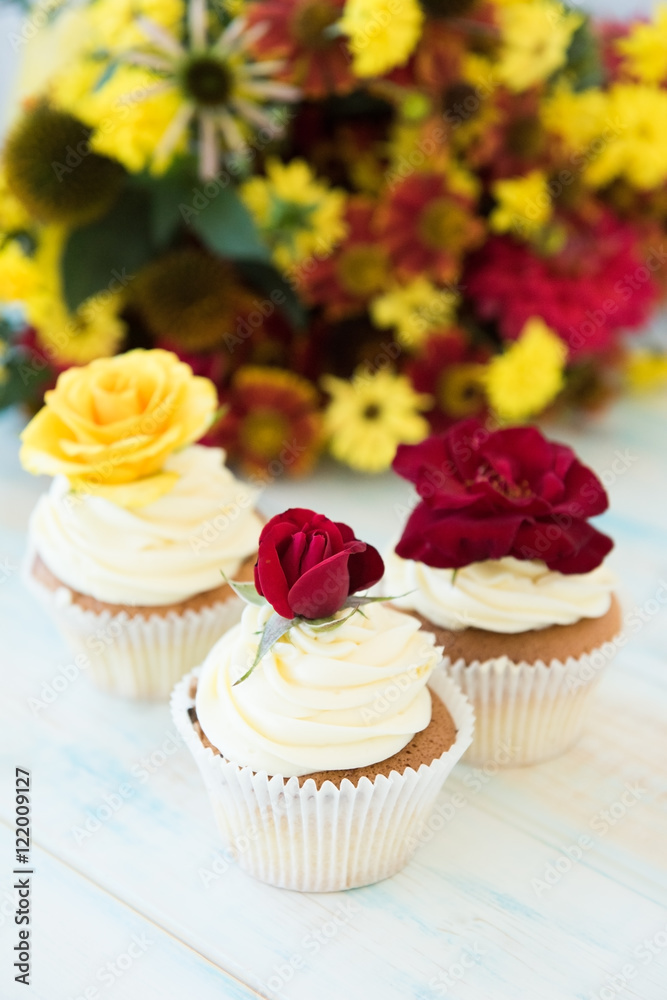 Three cupcakes with red and yellow roses. Selective focus