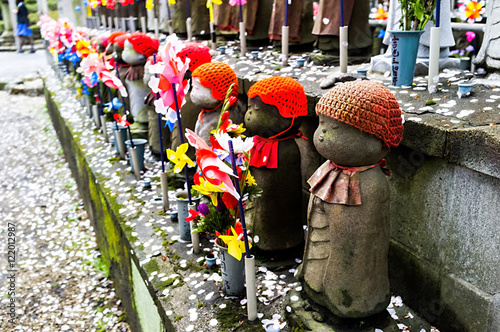 Jizo stone miscarried baby statues the guardian deity of children stand in front of cherry blossoms at Zojoji Temple, Tokyo, Japan. photo