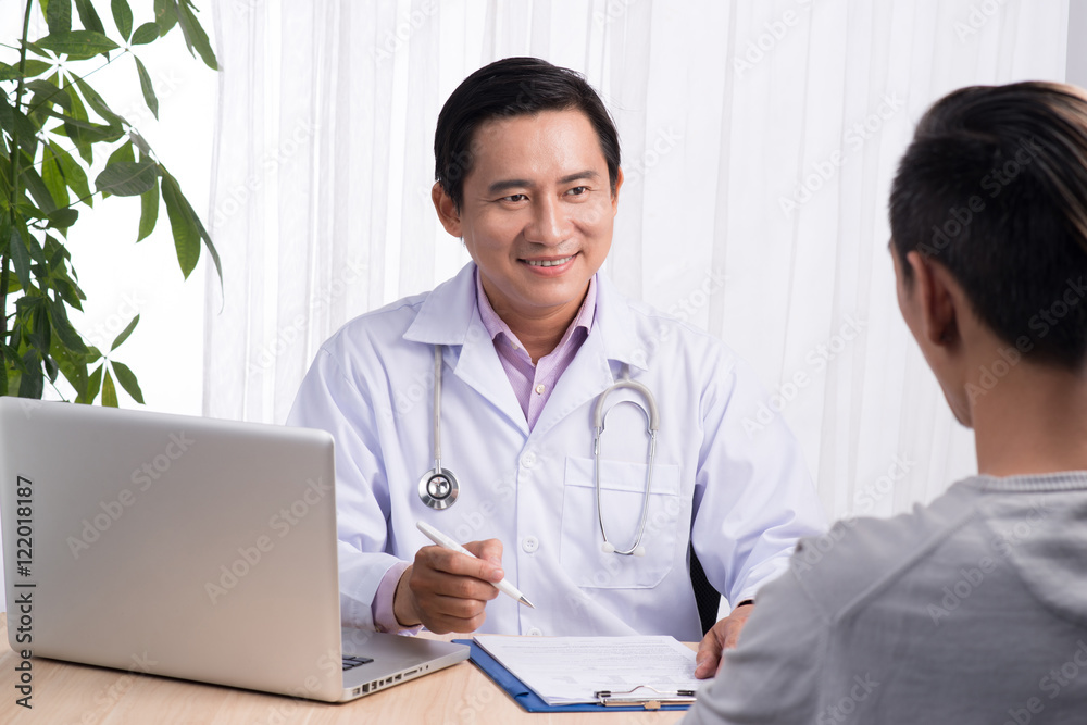 Confident asian male doctor discussing diagnosis with patient in Confident asian male doctor discussing diagnosis with patient in