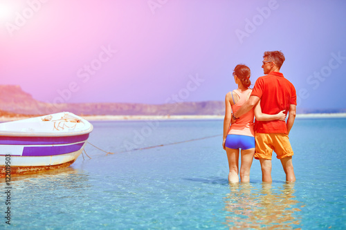 couple standing in the sea near the boat. They hold each other's hands