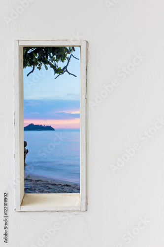 White wood wall window with sunset sea beach view.