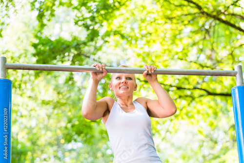 Woman exercising at high bar for better outdoor fitness