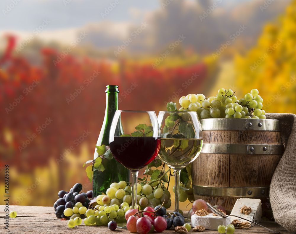 Red, white wine bottles and wine glasses, wooden barrel with nature background