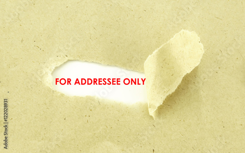 Text FOR ADDRESSEE ONLY appearing behind torn light brown envelo photo