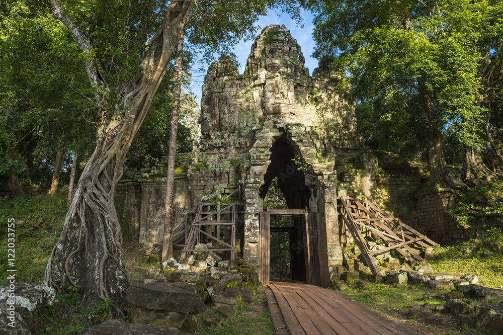 Scenic dappled jungle view of the Angkor Thom West Gate at the Angkor Temple complex near Siem Reap Cambodia