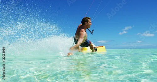 Young man kitesurfing in tropical blue ocean, extreme sport slow motion