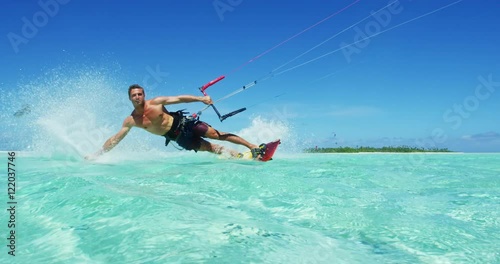 Young man kitesurfing in tropical blue ocean, extreme sport slow motion