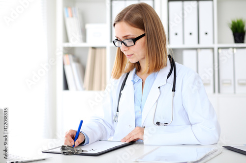 Female doctor writing a medical prescription at clipboard