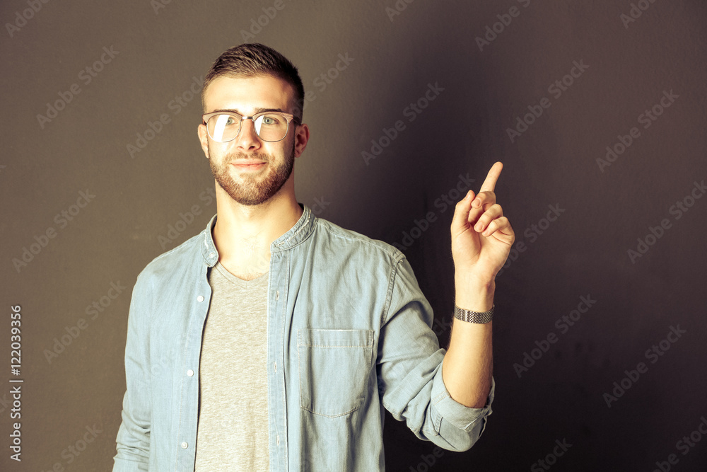 Portrait of a smiling young man pointing up Portrait of a smiling young man pointing up