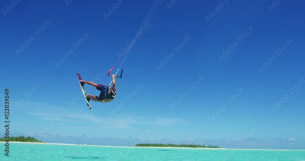 Young man kitesurfing in tropical blue ocean, extreme sport slow motion