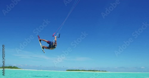 Young man kitesurfing in tropical blue ocean, extreme sport slow motion