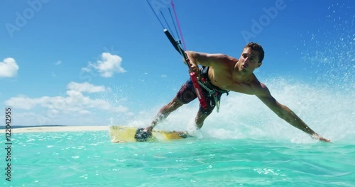 Young man kitesurfing in tropical blue ocean, extreme sport slow motion