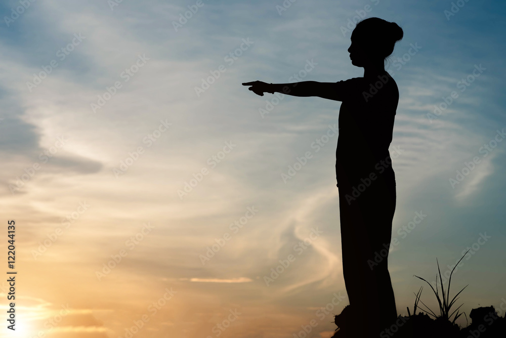 silhouette young woman pointing forward  in sunset sky