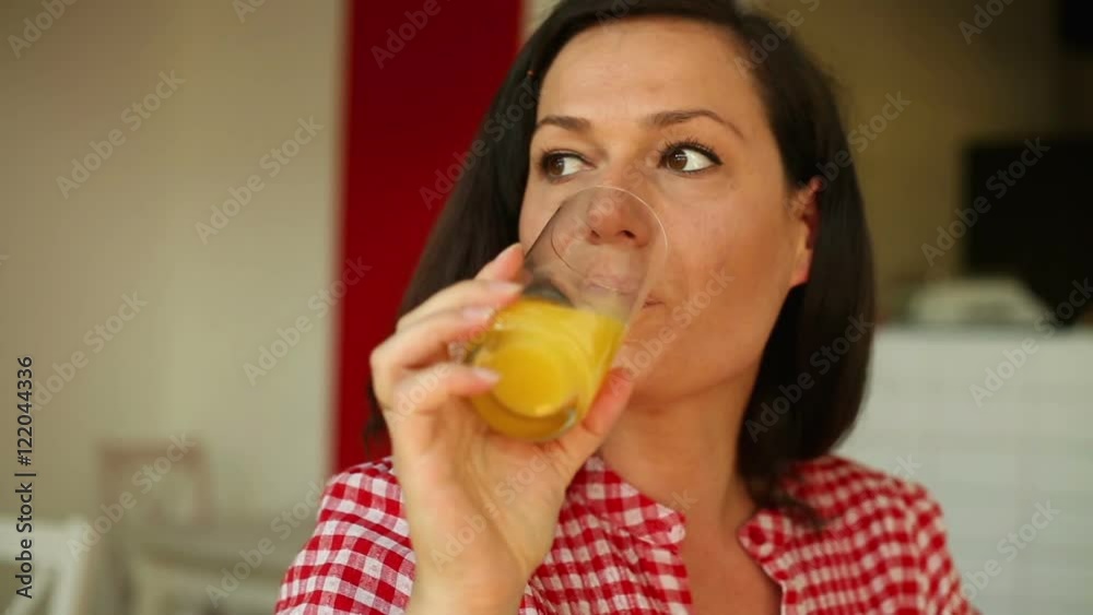Young woman smiling and drinking orange juice in a cafe
Young woman smiling and drinking orange juice in a cafe