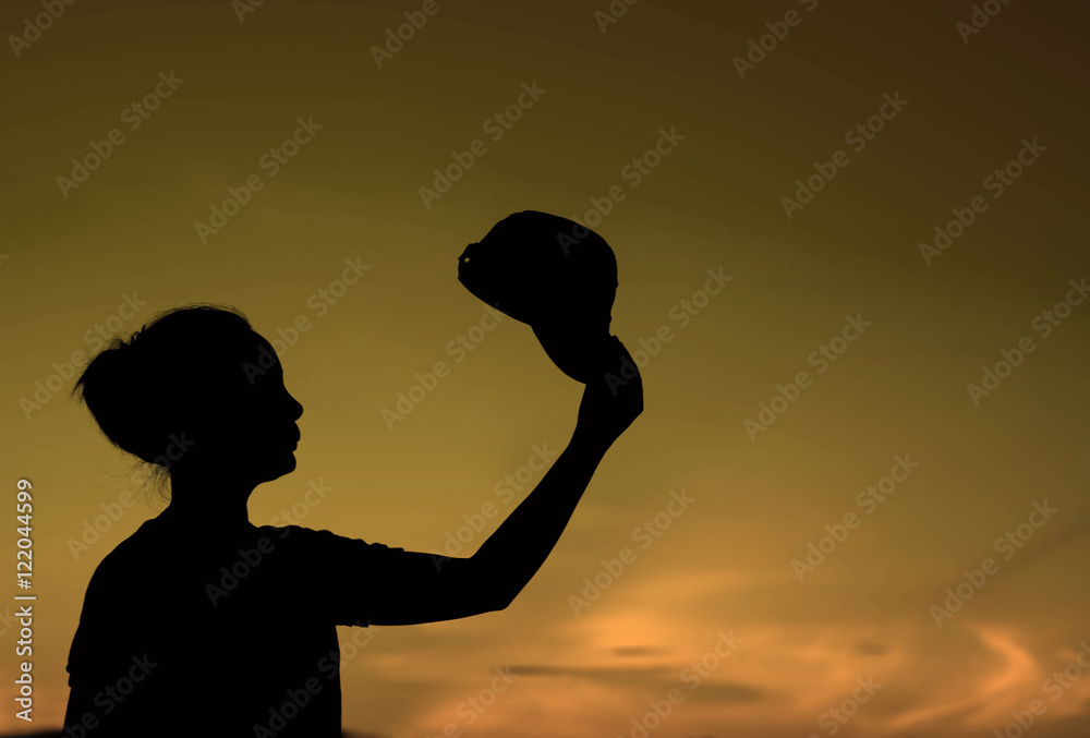 Silhouette of woman in hat on sunset