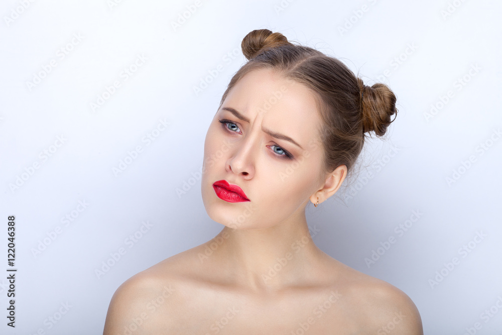 Portrait of a young pretty woman with trendy makeup bright red lips funny bun hairstyle and bare shoulders act the ape against white studio background Portrait of a young pretty woman with trendy makeup bright red lips funny bun hairstyle and bare shoulders act the ape against white studio background