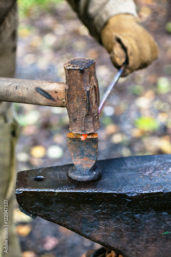 Blacksmith chops rod with sledgehammer and chisel