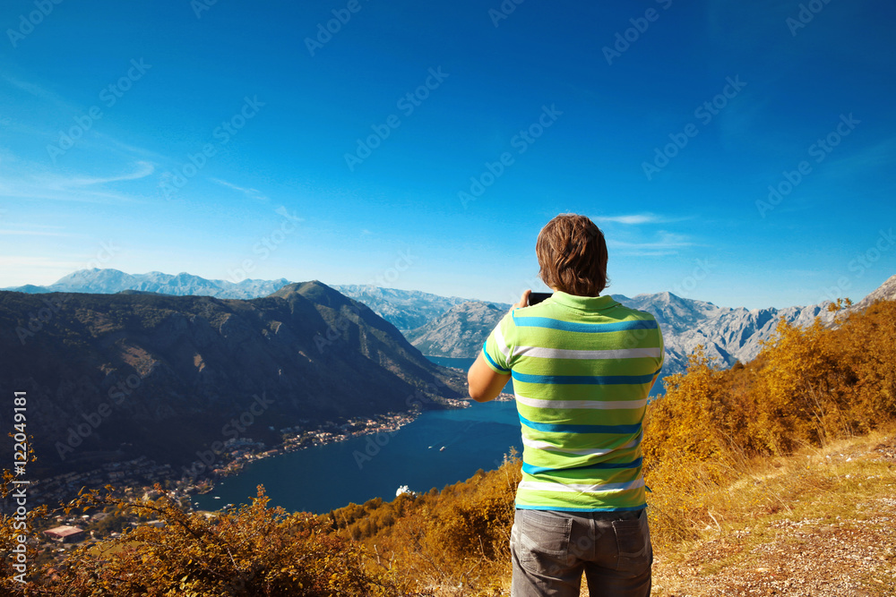 Kotor. Montenegro. Back view of young man tourist taking photo o