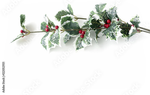 Artificial holly branch - ilex aquifolium, with fruits, glass stones and glitter isolated on white background with copy space. 