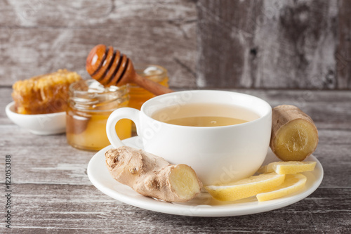 A white cup of green natural tea with ginger  lemon and honey on wooden rustic background. Healthy drink. Hot winter beverage concept.