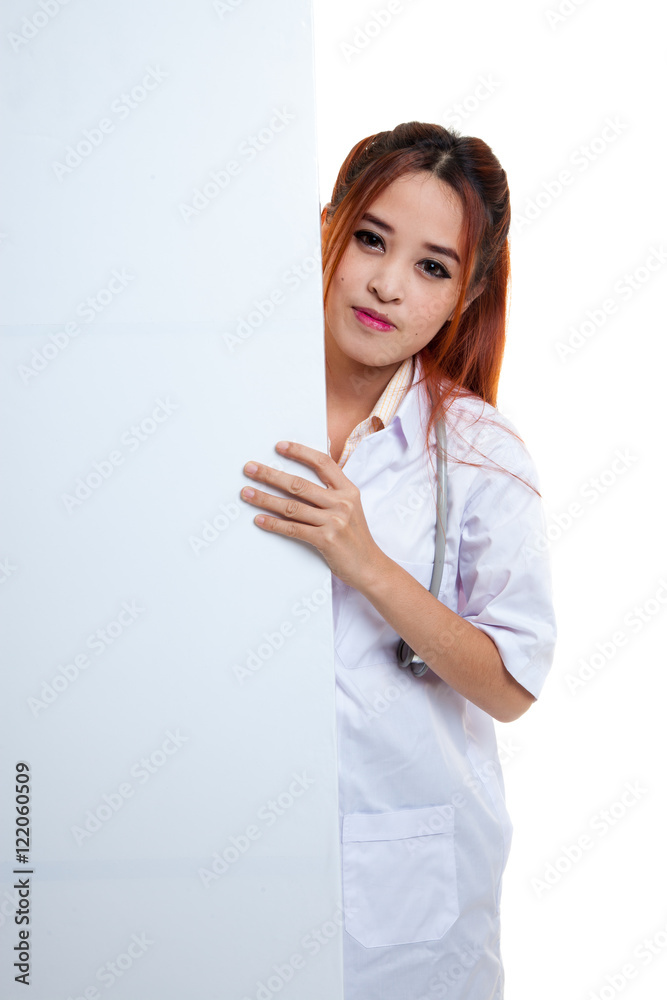 Young Asian female doctor peeking from behind blank sign billboa Young Asian female doctor peeking from behind blank sign billboa