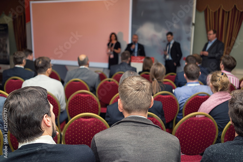 four speaker at a business conference , and a rear view of the audience