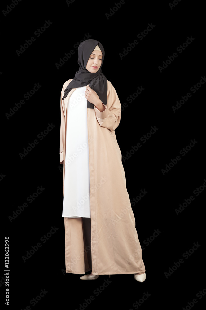 Muslim woman in a beautiful Islamic dress in full growth, isolated on a black background