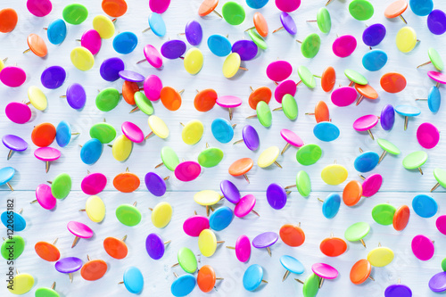 Colorful push pins on blue wooden background, close up.