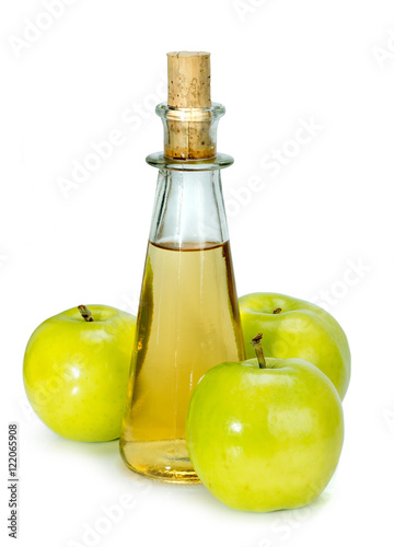 apple cider vinegar in a glass vessel and green apples