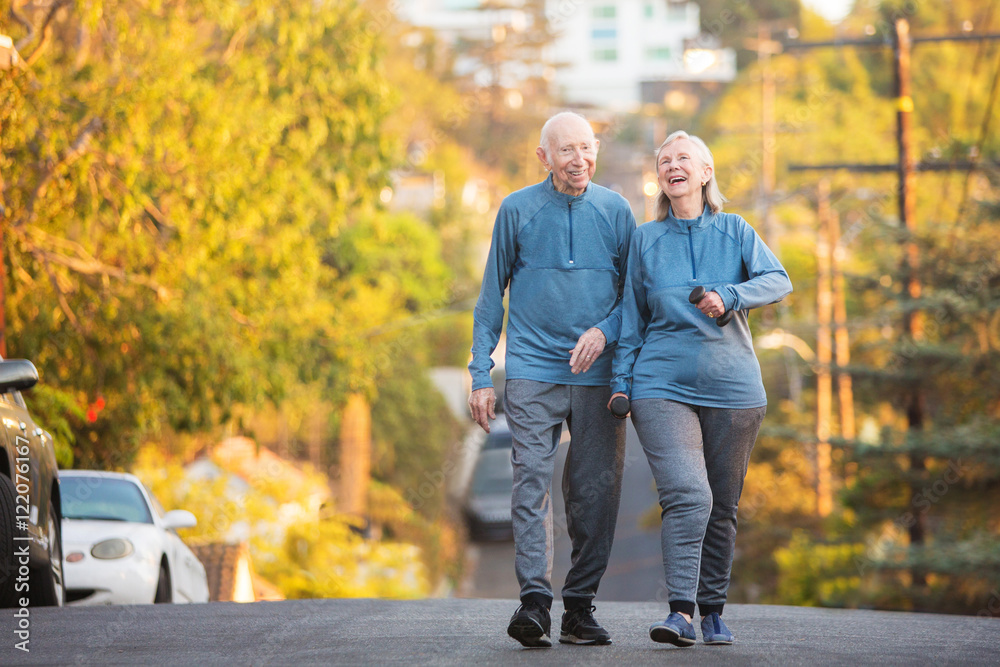 Obraz premium Laughing couple walking along street on hill