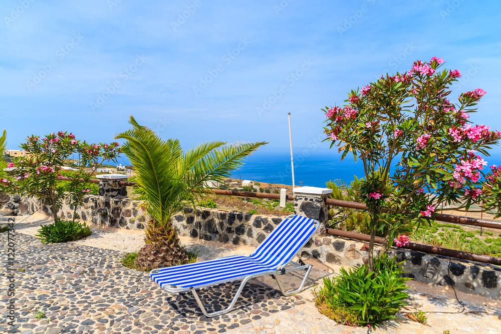 Sunbeds on sunny terrace with view of coast, Santorini island, G