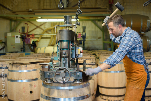 Fototapete cooper at work hammering top on to wooden barrel