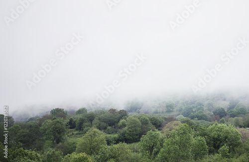 Panorama horizon view of scenery foggy hills Northern Spain forest. Sunset in the mountain natural autumn landscape park. Green valley on background dramatic sky and clouds. Travel mockup concept 