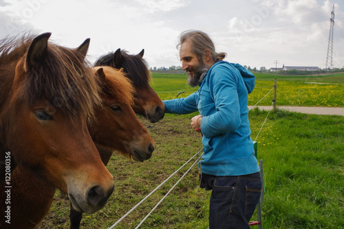 man speaking with horses on a meadow at summer time, whisperer