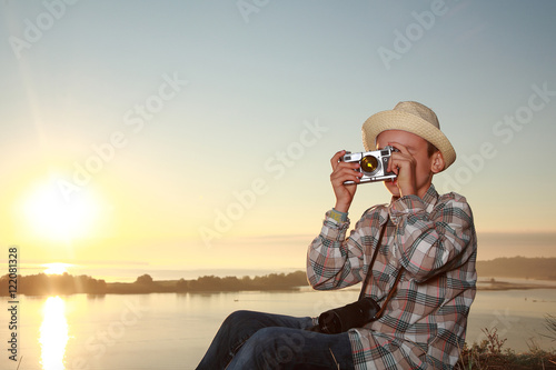 мальчик фотографирует на закате солнца photo