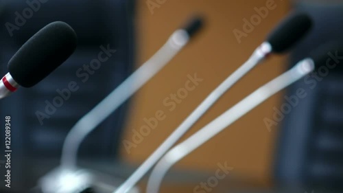 Dolly shot of microphones in modern conference room. Shallow DOF