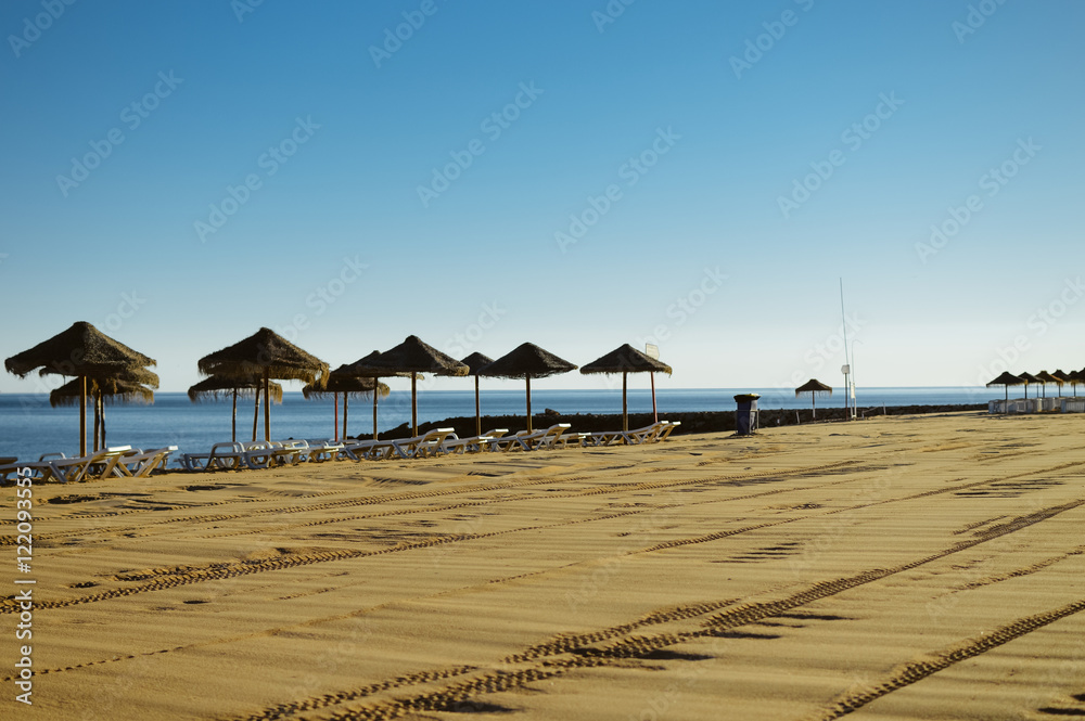 Obraz premium Beautiful view of beach with wicker umbrellas on the sunny blue sky outdoors background