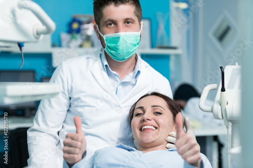 Dentist examining Patient teeth with a Mouth Mirror. Dentist is a Man  Patient is a Woman. Patient is Relaxed and not scared of Dentist.