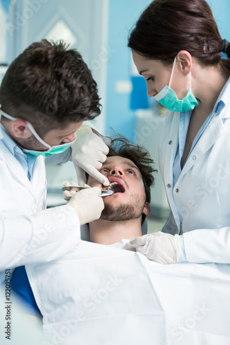 Dentistry education. Male dentist doctor teacher explaining treatment procedure to students group in dental clinic