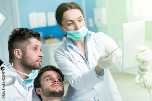 Dentistry education. Male dentist doctor teacher explaining treatment procedure to students group in dental clinic