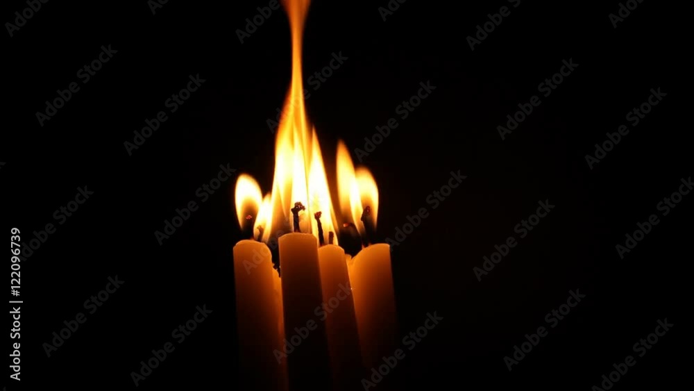 A group of candles burn together in the darkness. A group of candles burn together in the darkness.