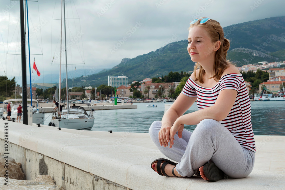 Obraz premium Girl sit meditation on the pier. Makarska riviera, Dalmatia, Croatia, Europe.